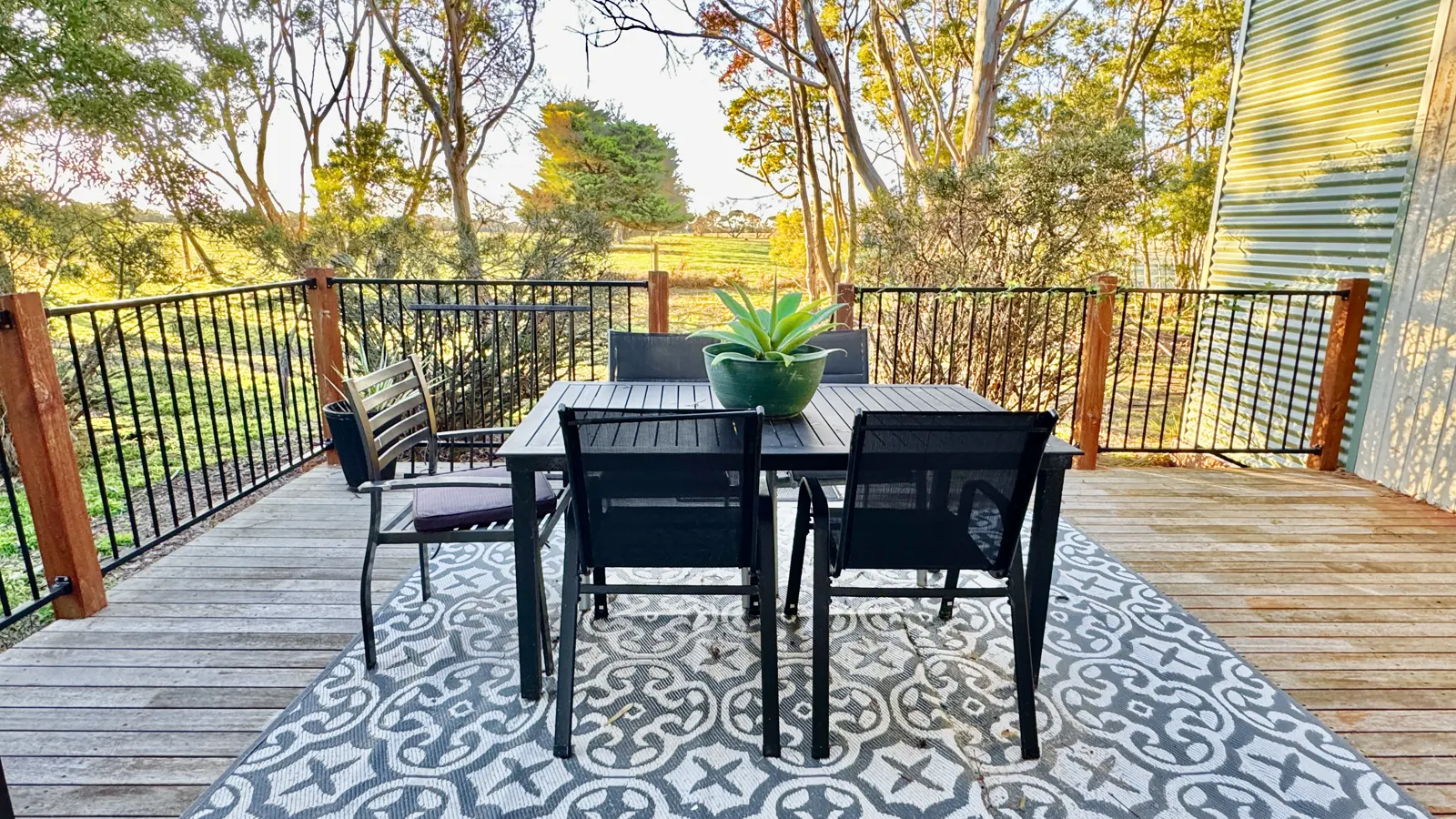 Outdoor dining table and chairs on the tree-lined private deck — Two-bedroom Villa 107, Cowes, Phillip Island