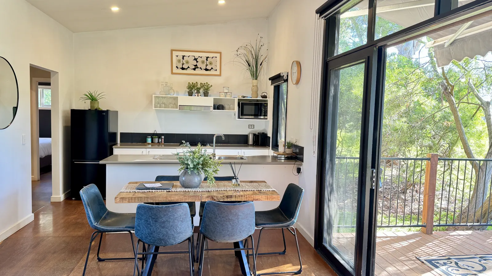 Self-contained kitchen and timber dining table beside doors to the deck — Three-bedroom Villa 115, Cowes, Phillip Island