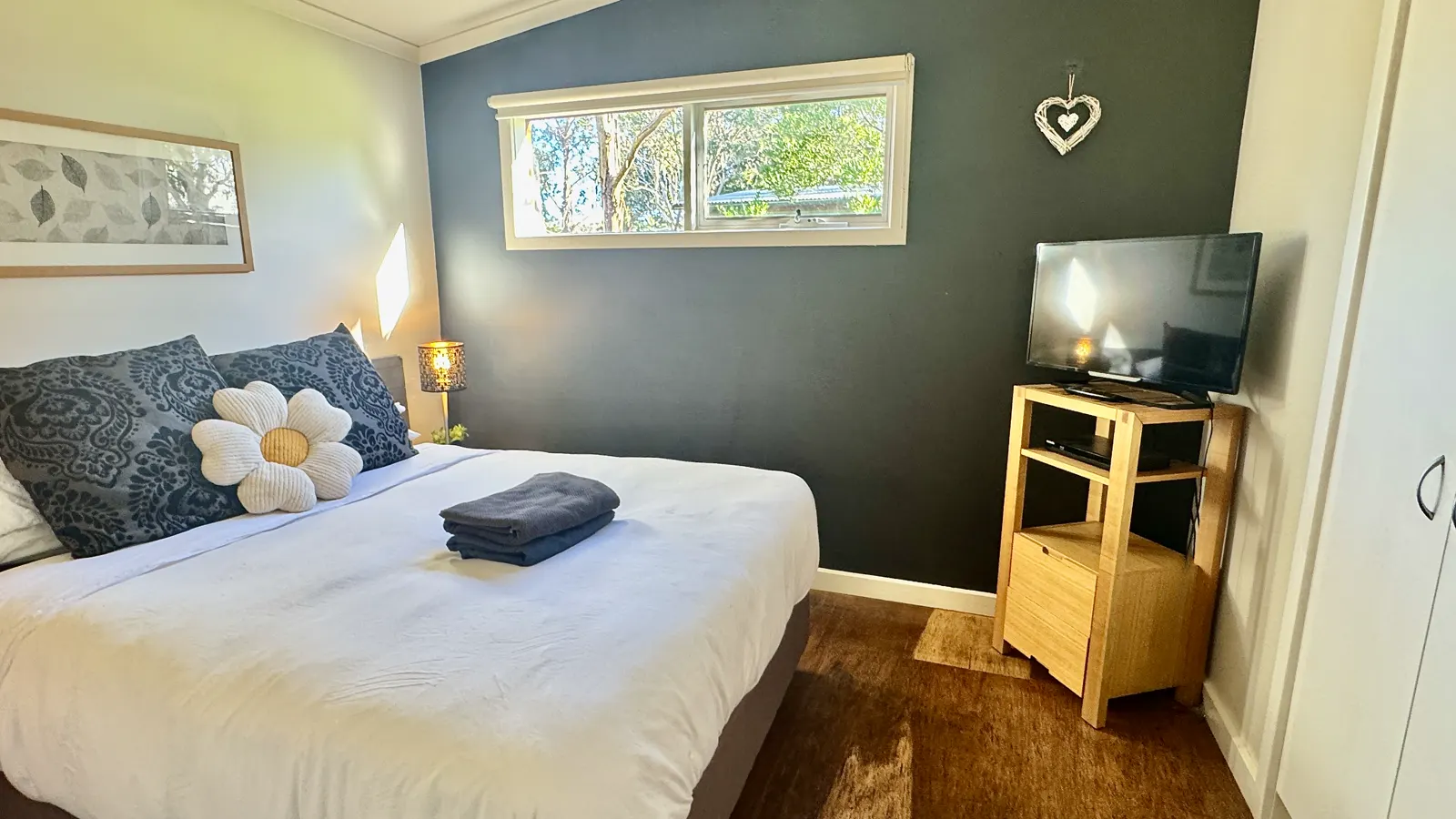 Bedroom with a flower cushion, warm bedside lighting and a small television — Three-bedroom Villa 115, Cowes, Phillip Island