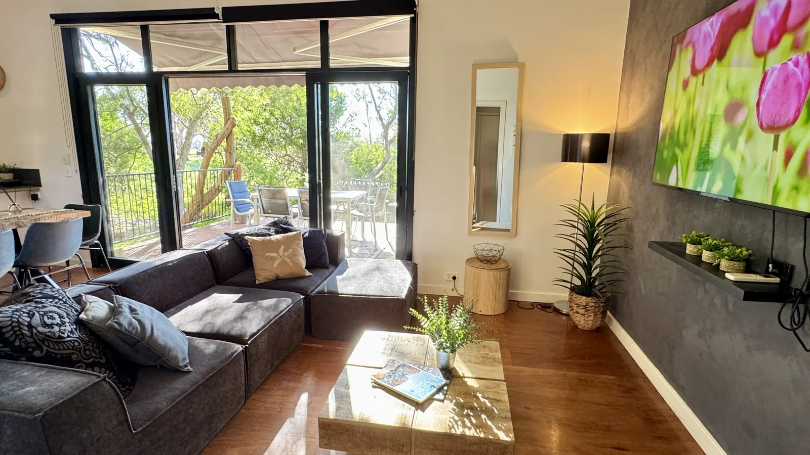 Living room with a dark sofa, coffee table and wall-mounted television — Three-bedroom Villa 115, Cowes, Phillip Island