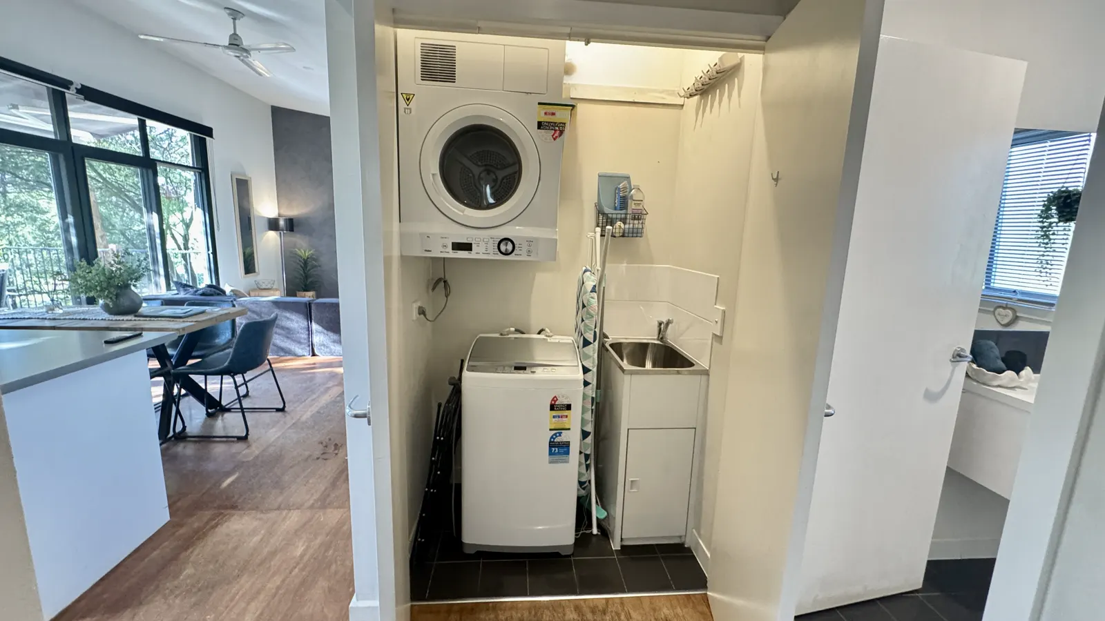 Laundry cupboard with washing machine and tumble dryer beside the living area — Three-bedroom Villa 115, Cowes, Phillip Island