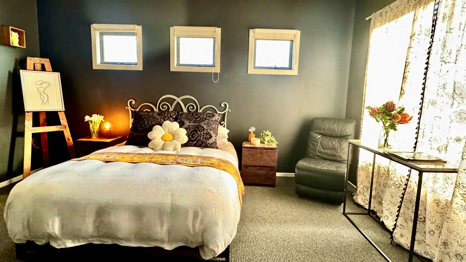 Bedroom with a white quilt, flower cushion and warm bedside lamps — Coastal Tones holiday home, Cowes, Phillip Island