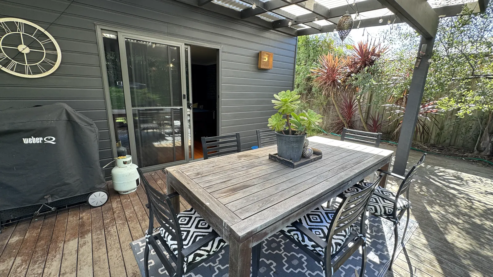 Outdoor dining table on the timber deck beside sliding doors to the house — Coastal Tones holiday home, Cowes, Phillip Island