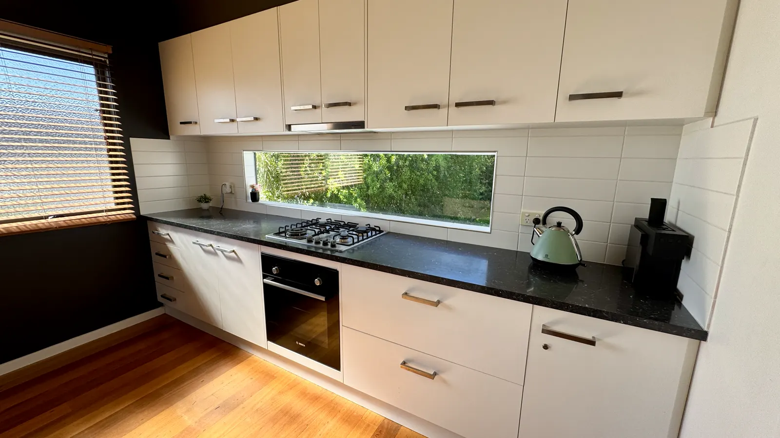 White kitchen cabinetry with an oven and a window above the sink — Coastal Tones holiday home, Cowes, Phillip Island