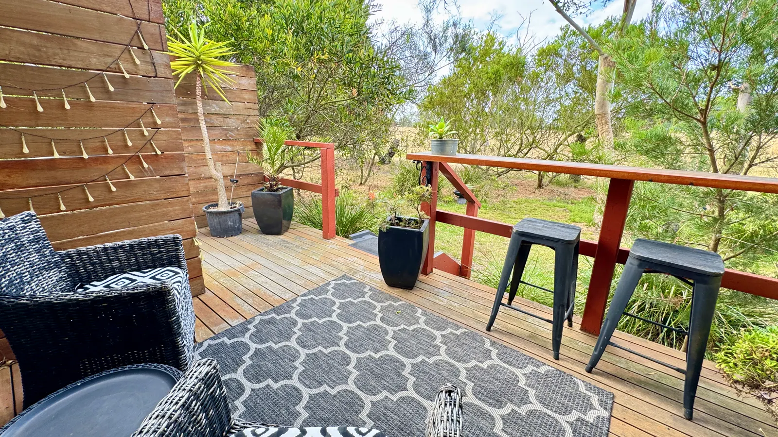 Furnished timber deck with bar seating overlooking trees and rural fields — Couples Private Spa Retreat Villa 117, Cowes, Phillip Island