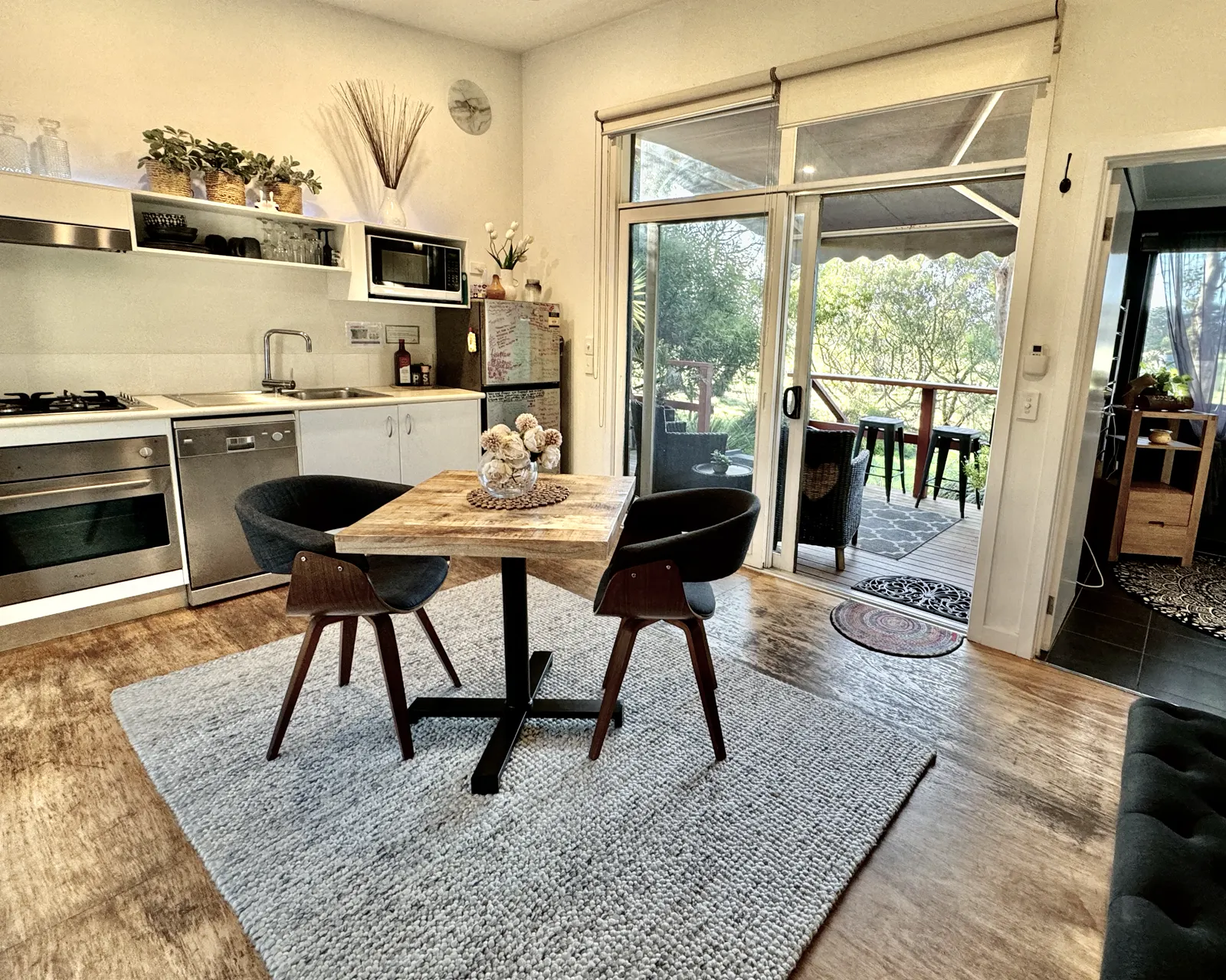 Self-contained kitchen and round dining table opening onto the private deck — Couples Private Spa Retreat Villa 117, Cowes, Phillip Island